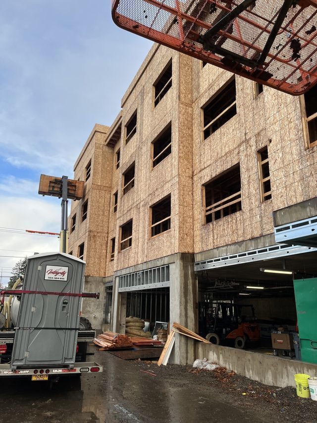 A portable toilet is parked in front of a building under construction