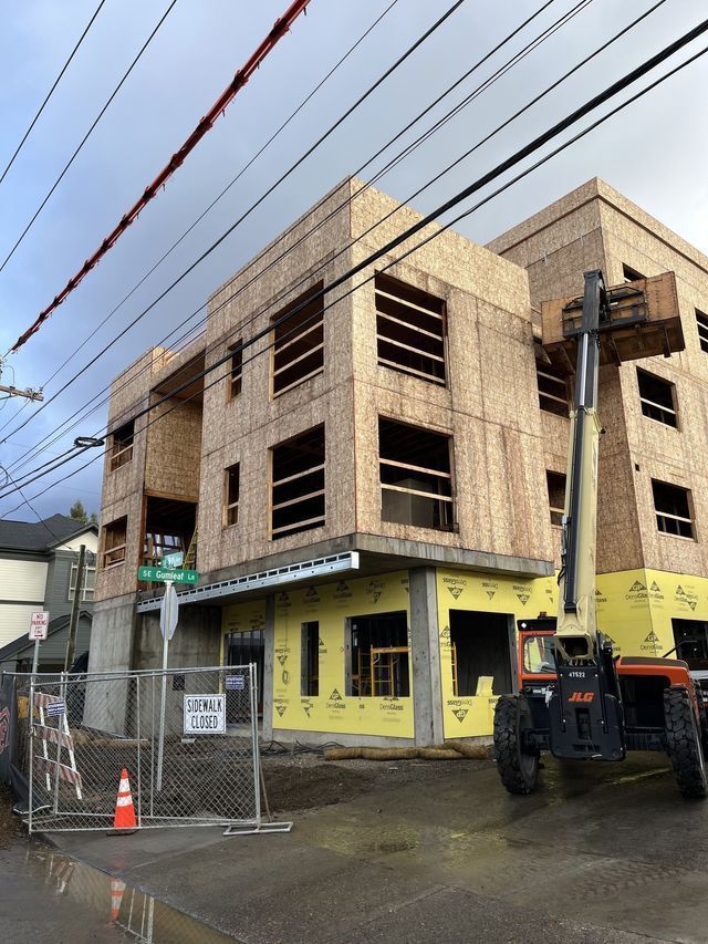 A large building under construction with a forklift parked in front of it