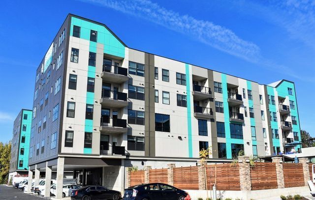 A large apartment building with a car parked in front of it.