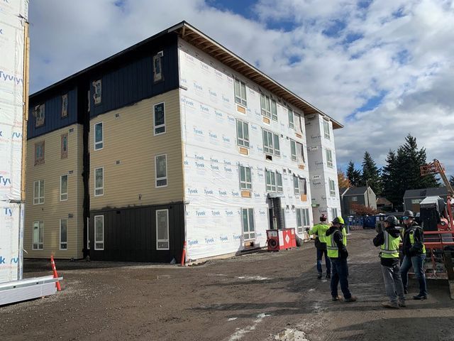 A group of people are standing in front of a building under construction.