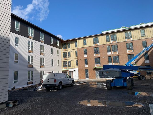 A white van is parked in front of a building under construction