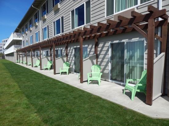 A row of green chairs under a pergola in front of a building