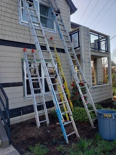 Three ladders are sitting on the side of a house.