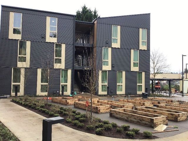 A large building with a lot of windows and a lot of wooden planters in front of it.
