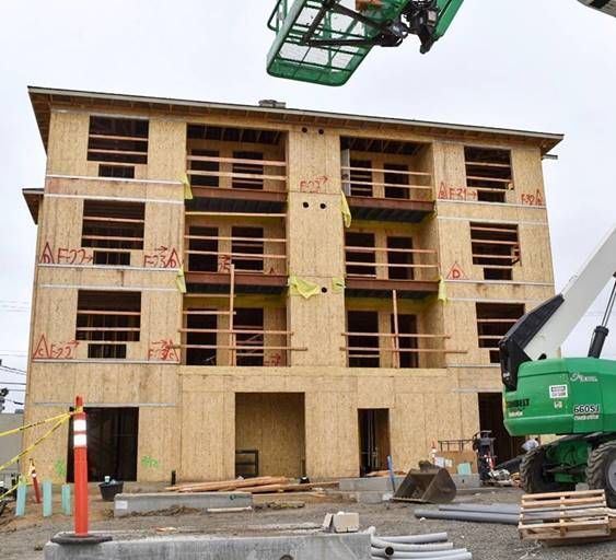 A green crane is lifting a large wooden building