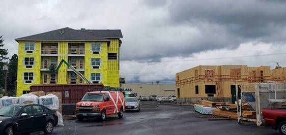 A red van is parked in front of a building under construction.