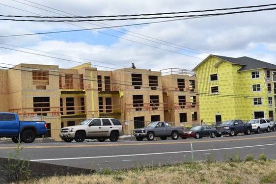 A row of cars are parked in front of a building under construction.