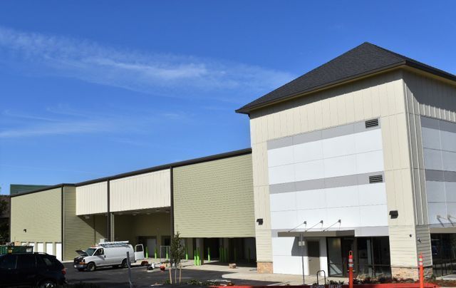 A white van is parked in front of a large building.