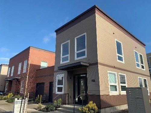 A large brick building with a lot of windows is sitting next to a smaller brick building.