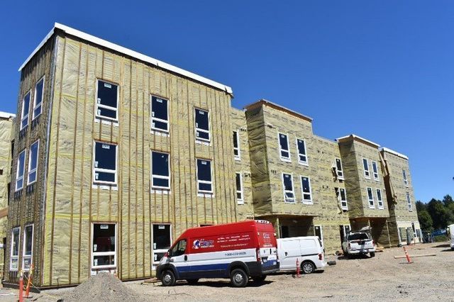 Two vans are parked in front of a building under construction.