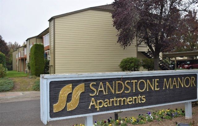 A sign for sandstone manor apartments is in front of a building