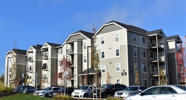A large apartment building with cars parked in front of it