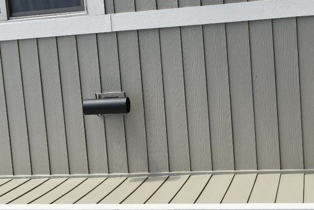 A black pipe is attached to the side of a building