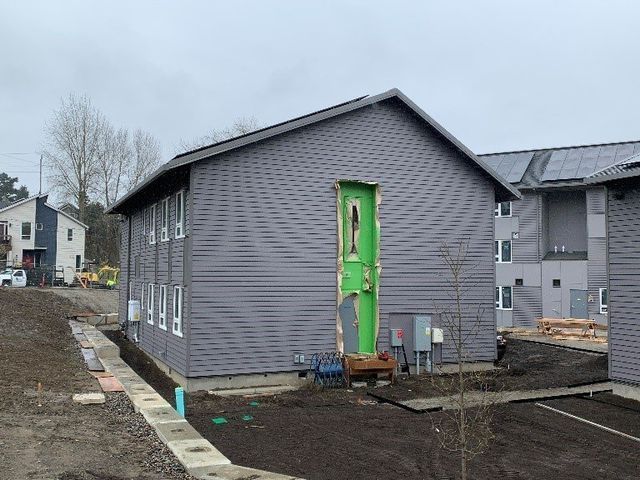 A gray building with a green door is being built.