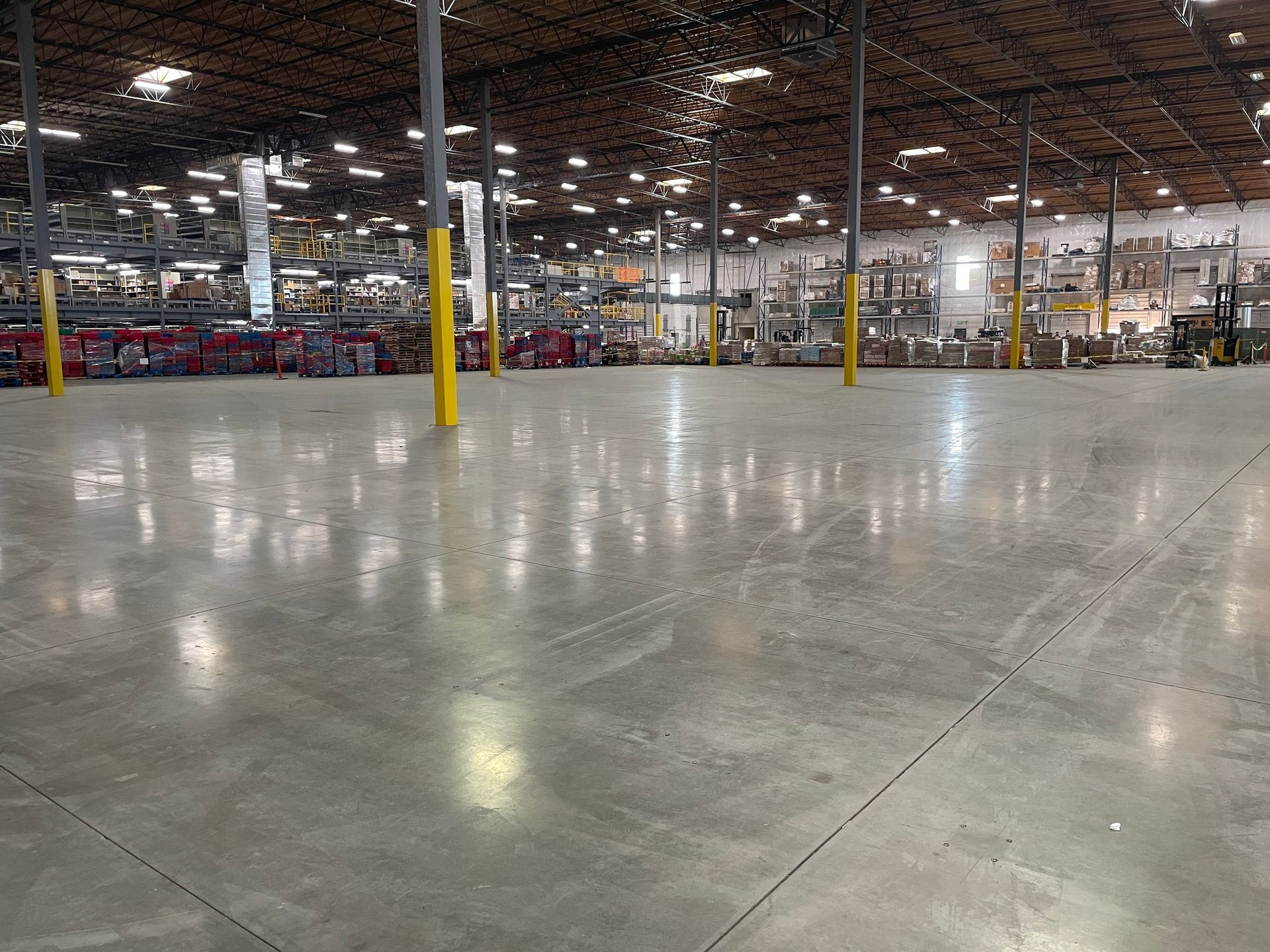 Empty warehouse interior with polished concrete floor, yellow support columns, and industrial lighting