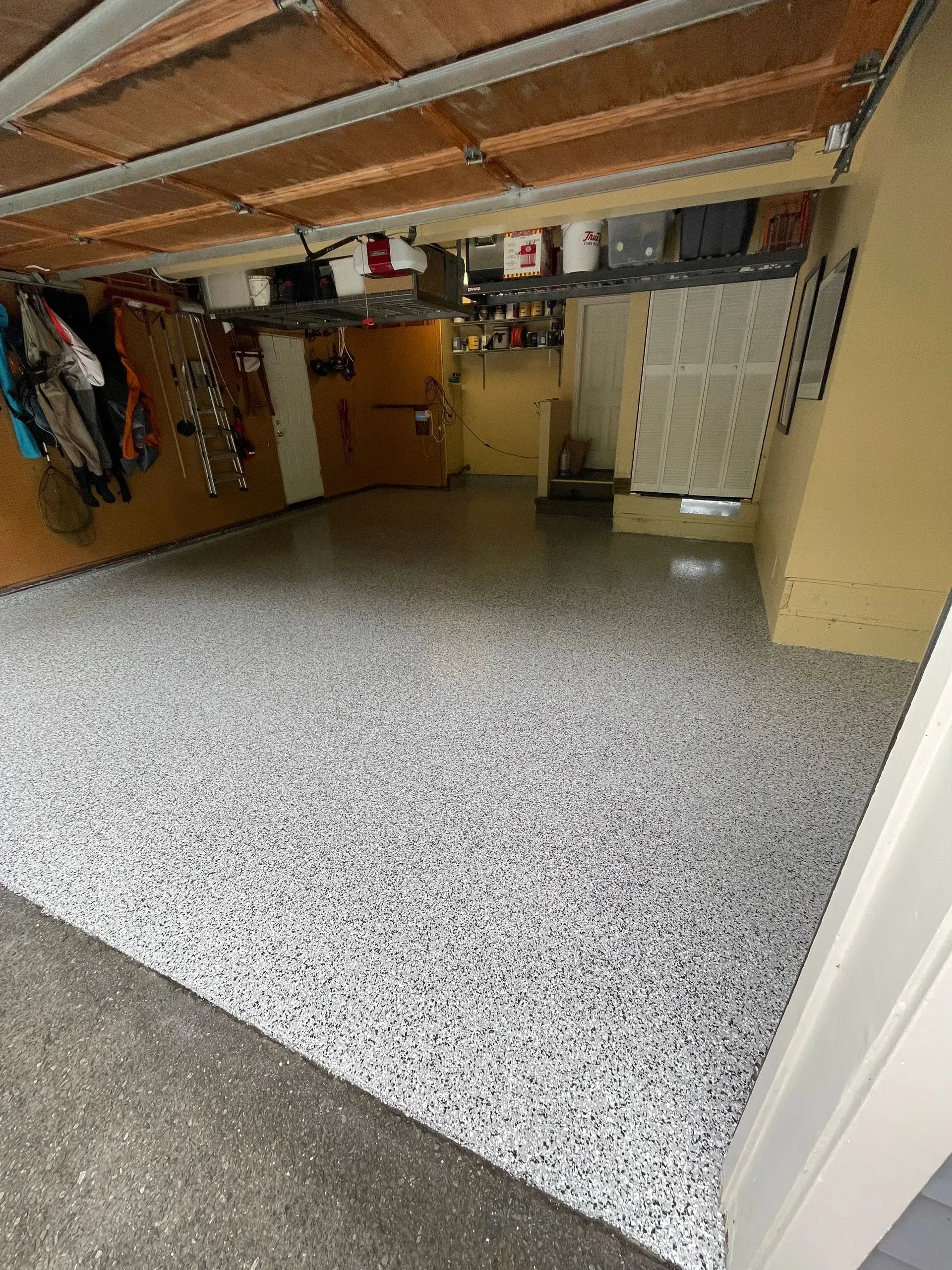 Garage with a gray and white speckled epoxy floor.