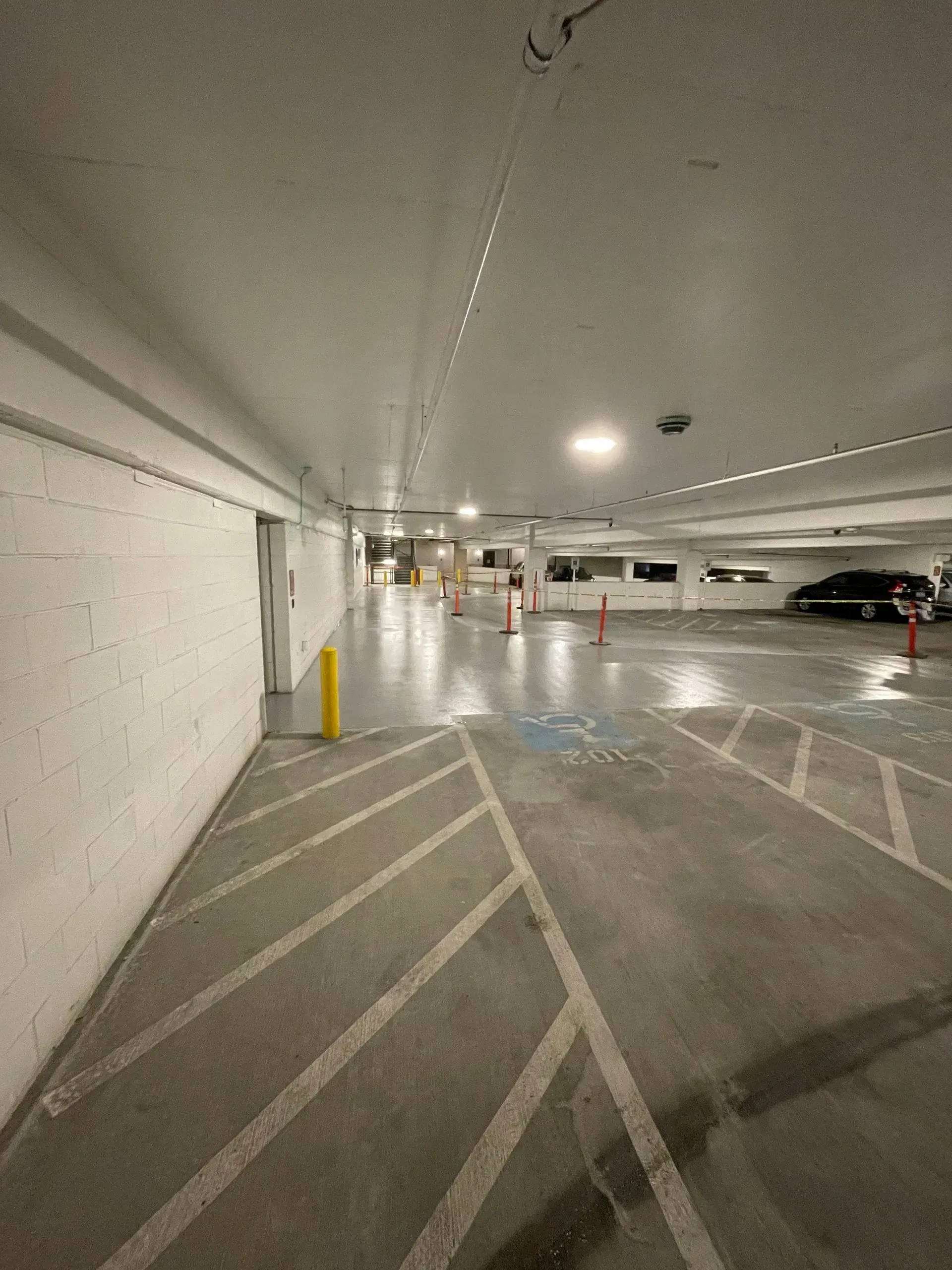 Interior view of an empty parking garage. Concrete floor with white painted lines and walls.