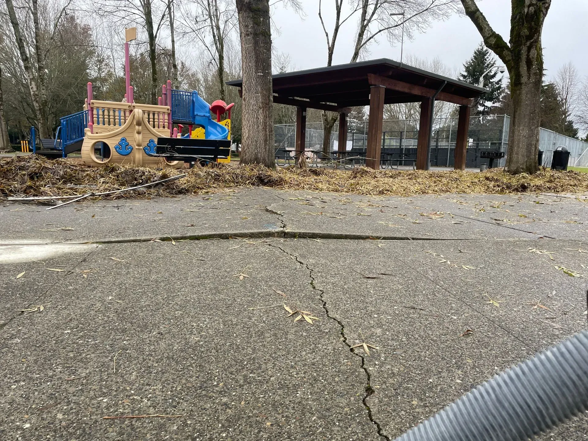 A playground and a gazebo with fallen leaves on the ground.