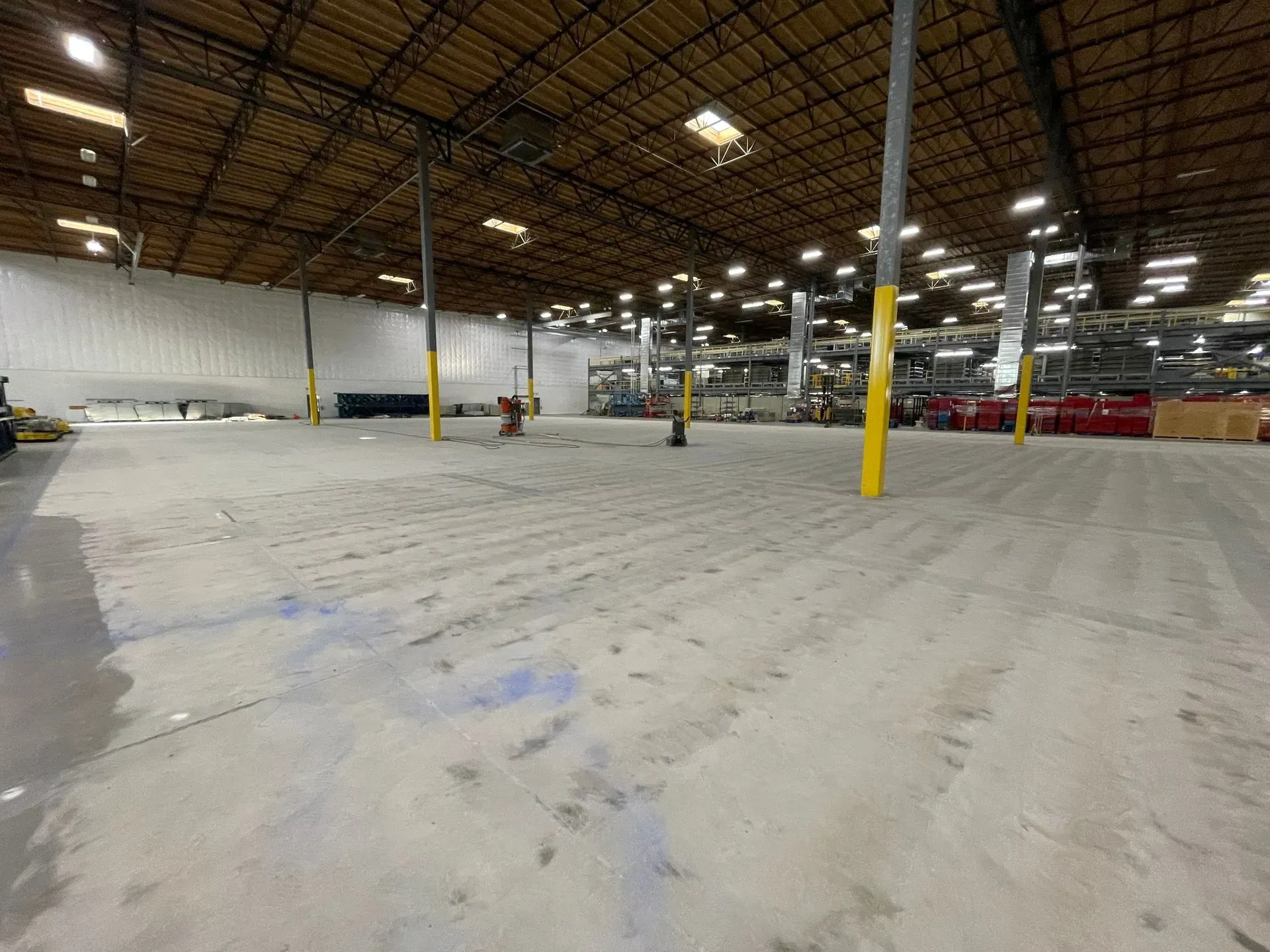 Large empty warehouse space with concrete floor, metal pillars, and high ceiling.
