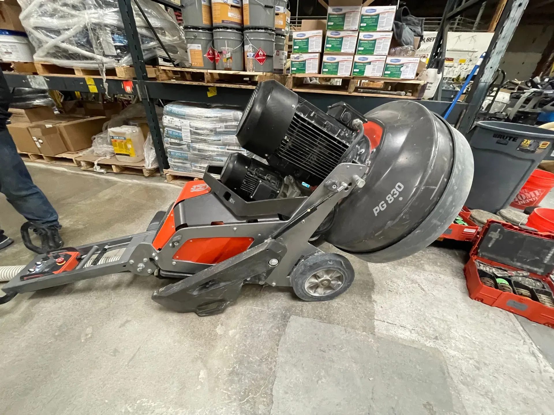 A large, gray concrete grinder in a warehouse setting.