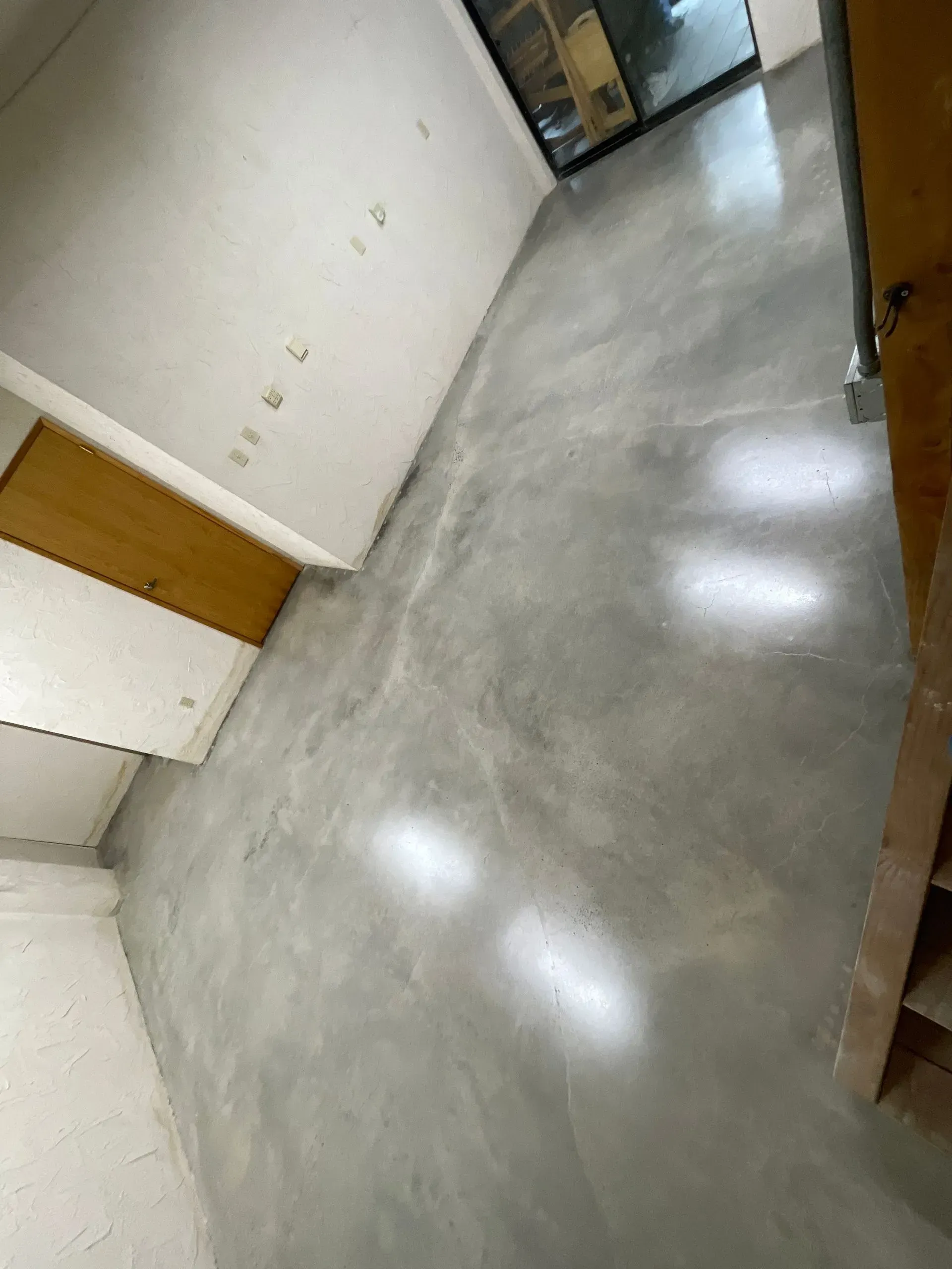 A room with a polished gray concrete floor and white walls.