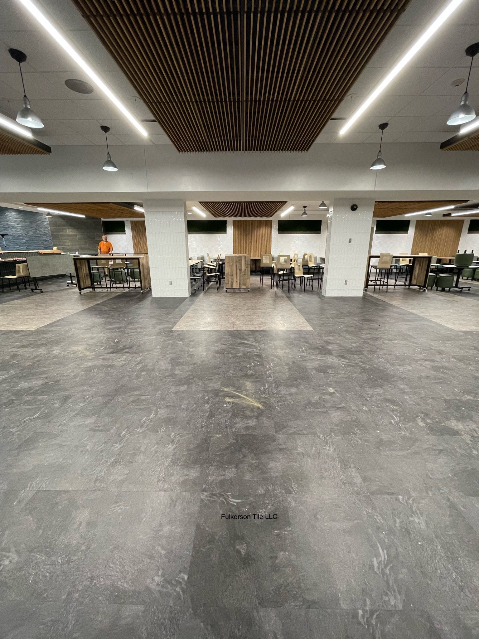 Large empty room with concrete floor, white pillars, and wood paneling on ceiling.