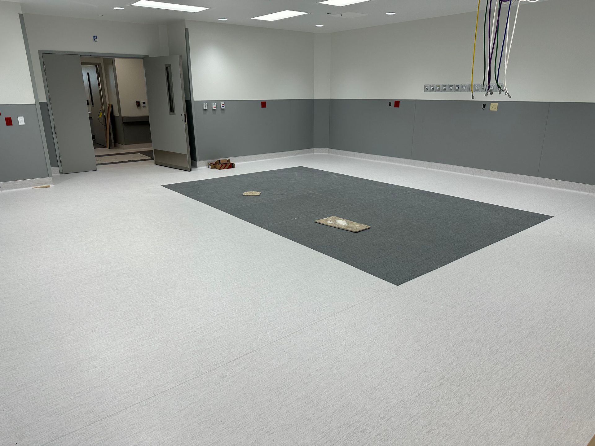 Empty medical room with gray and white walls and floor, and a gray floor mat.