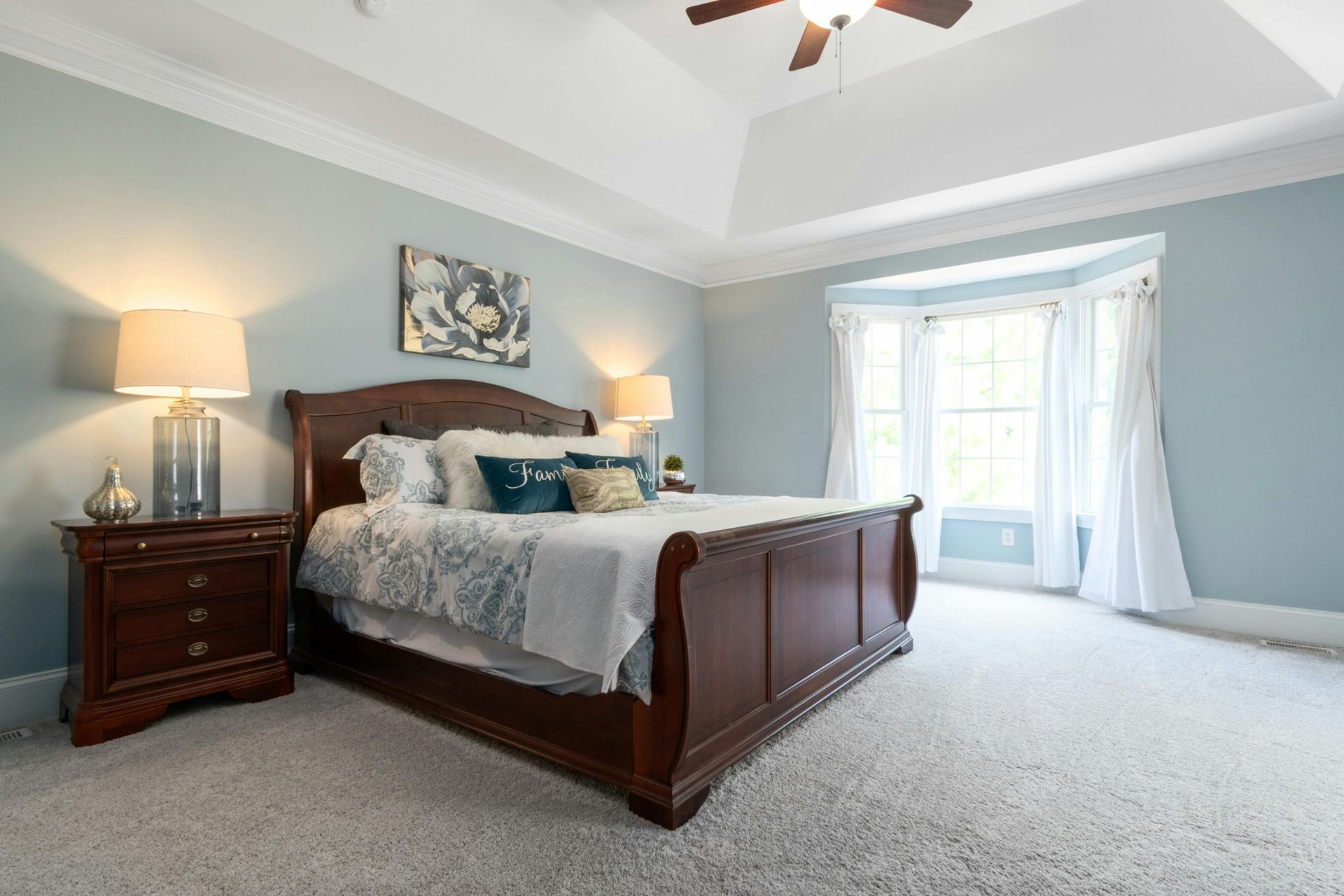 Bedroom with a dark wooden bed, nightstand, and window with white curtains; light blue walls and ceiling.