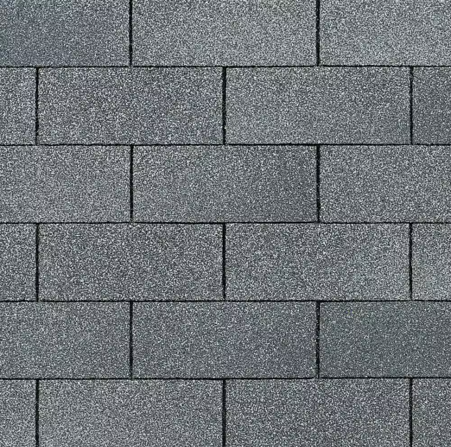Close-up of builder-grade 3-tab asphalt shingles showing a basic flat shingle profile used for standard roof replacement applications.