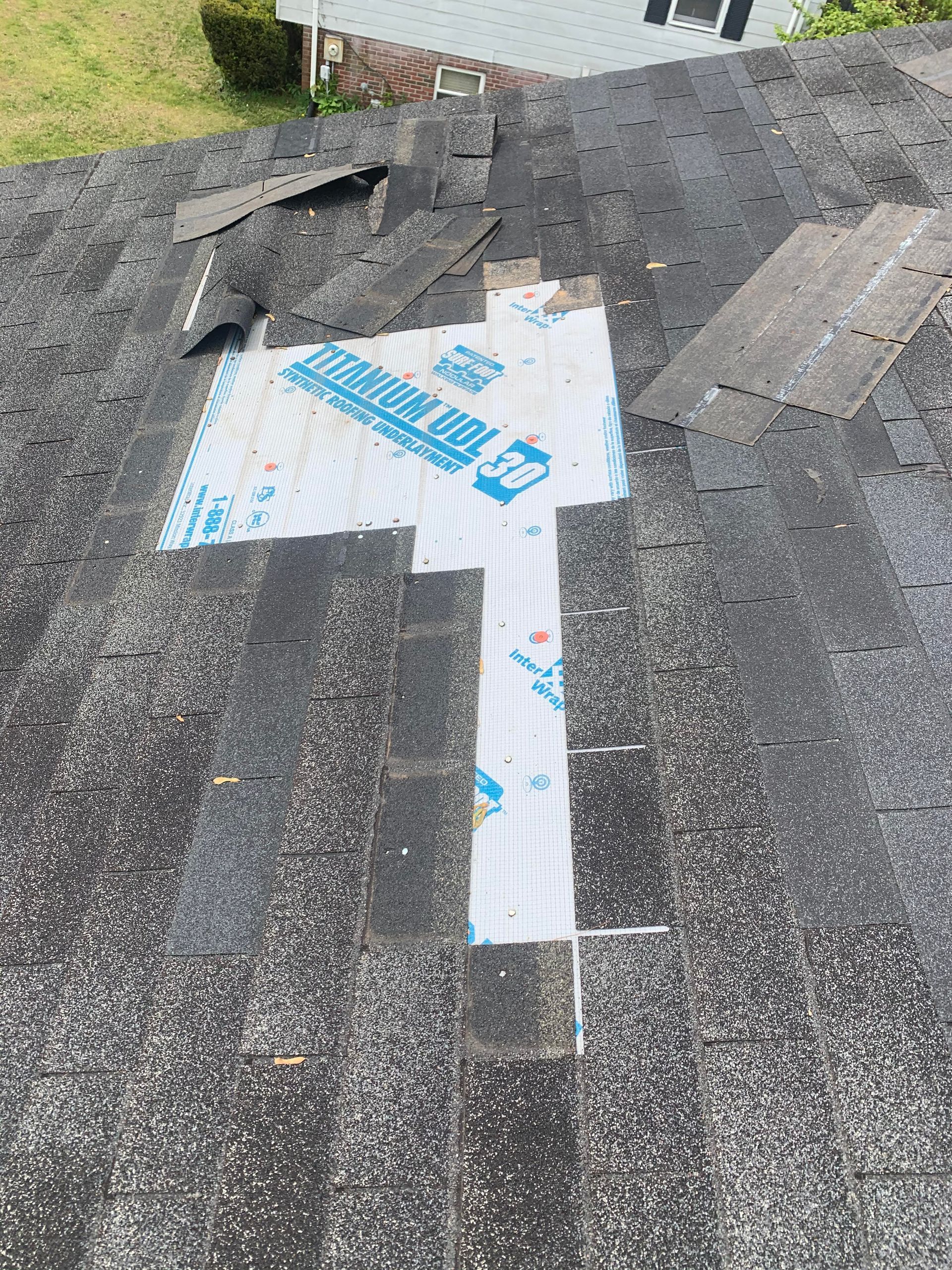 Asphalt shingle roof repair in progress where damaged shingles have been removed and the roof deck prepared for replacement materials.