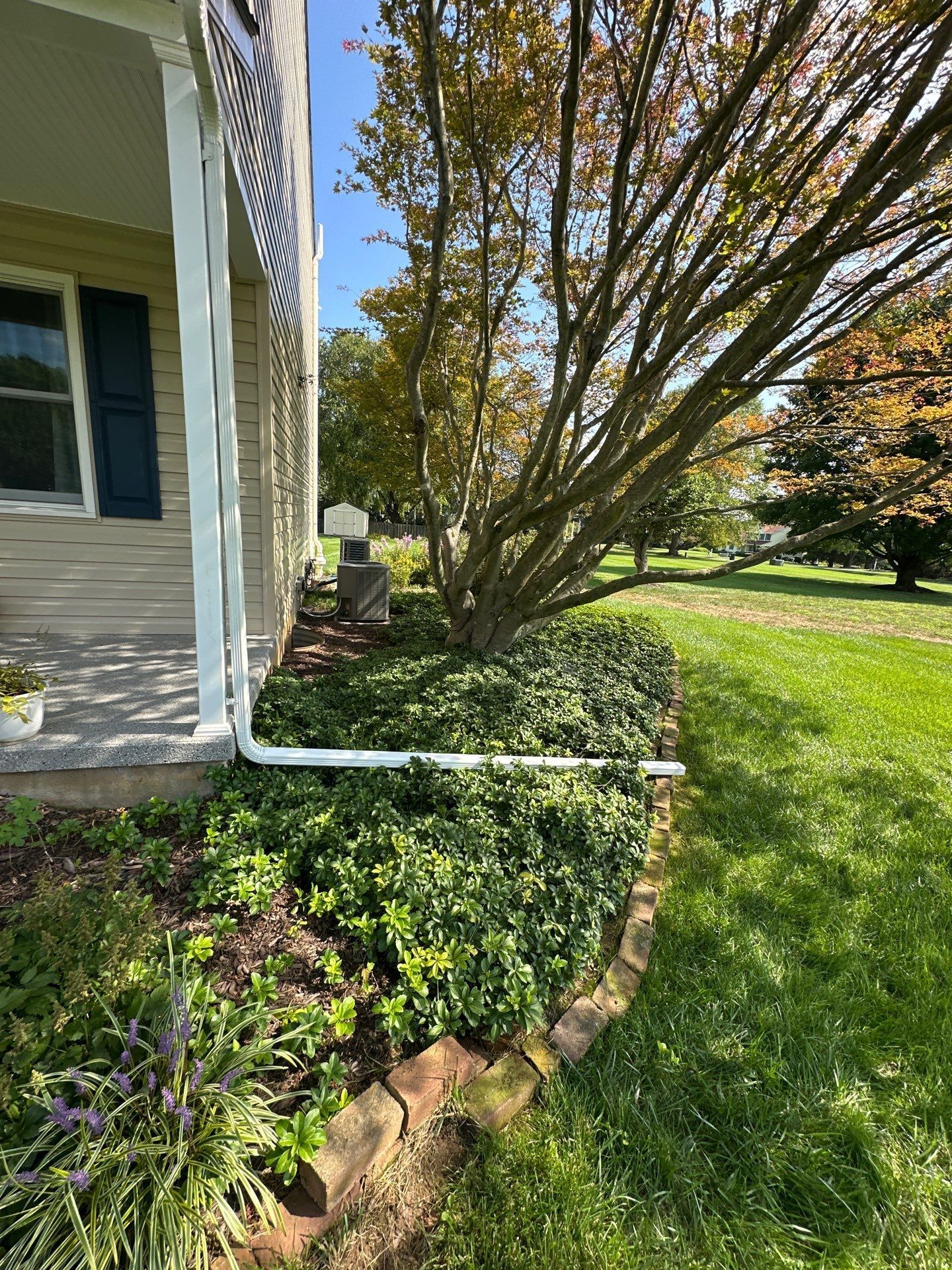 Downspout extension directing roof runoff away from a residential foundation