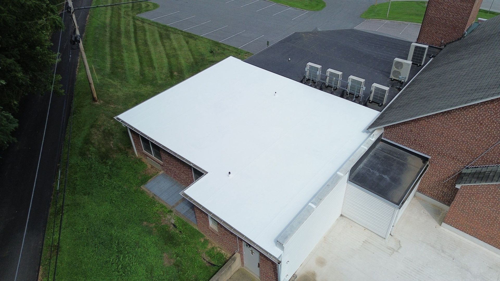 Low-slope roof section with a white membrane or coating system installed to repair and protect a vulnerable roof area.