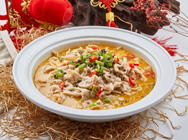 Bowl of creamy soup topped with green onions and red chilies on a decorative festive table runner