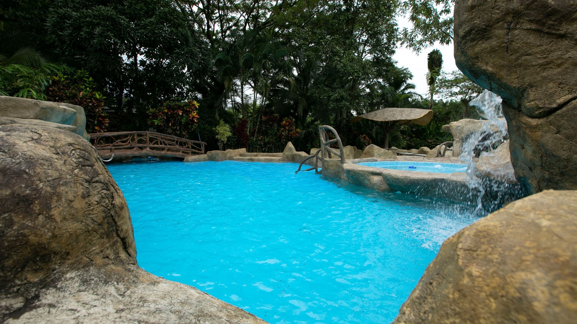 Piscina tropical con agua azul brillante, formaciones rocosas y vegetación circundante.