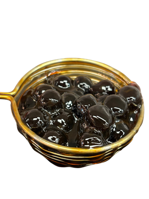 Dark brown boba pearls in a gold strainer, against a white background.