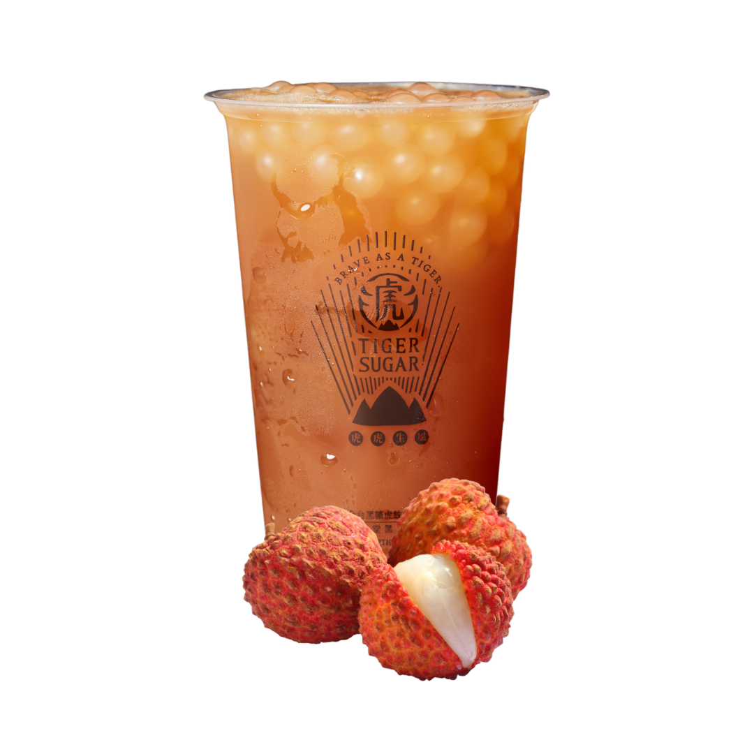 Lychee tea with tapioca pearls in a clear cup, lychees in front.