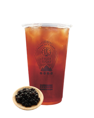 Tiger Sugar iced tea in a clear cup, with boba in a small wooden bowl.