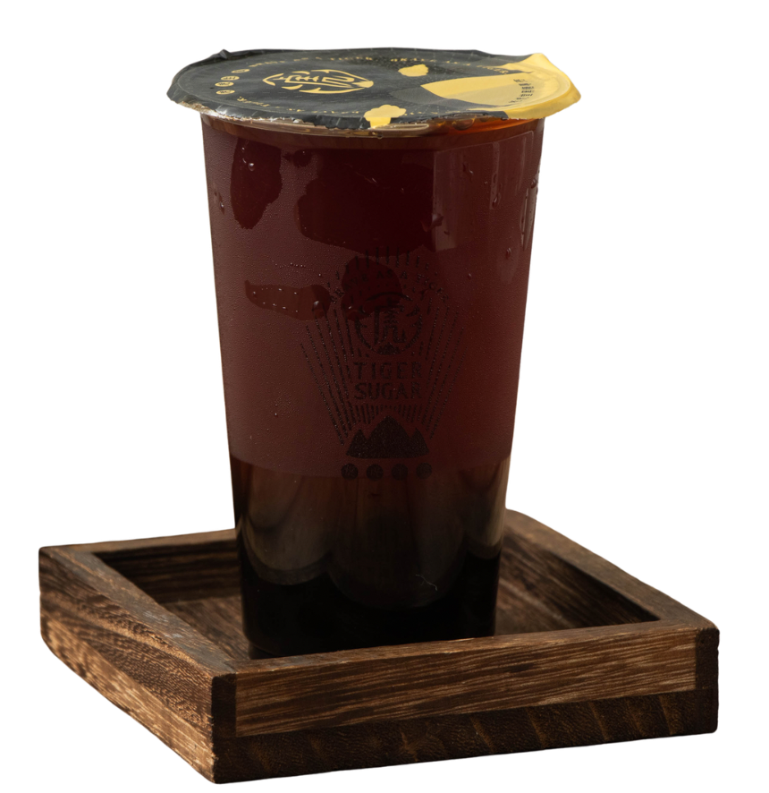 Iced tea in a clear plastic cup on a wooden tray, sealed with a black and gold lid.