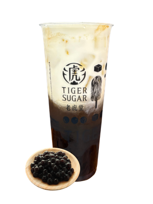 Tiger Sugar drink with brown sugar boba and cream, served in a clear cup with logo; boba on a wooden plate.