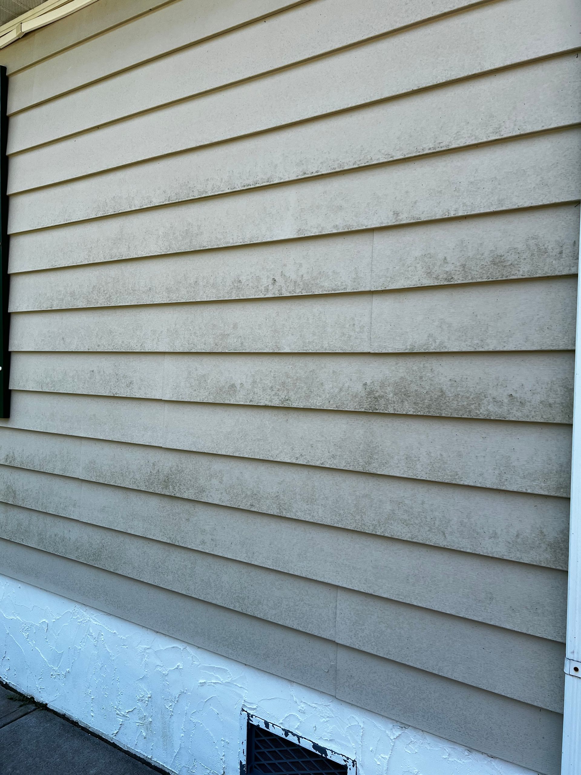 The side of a house with dirty siding and a window
