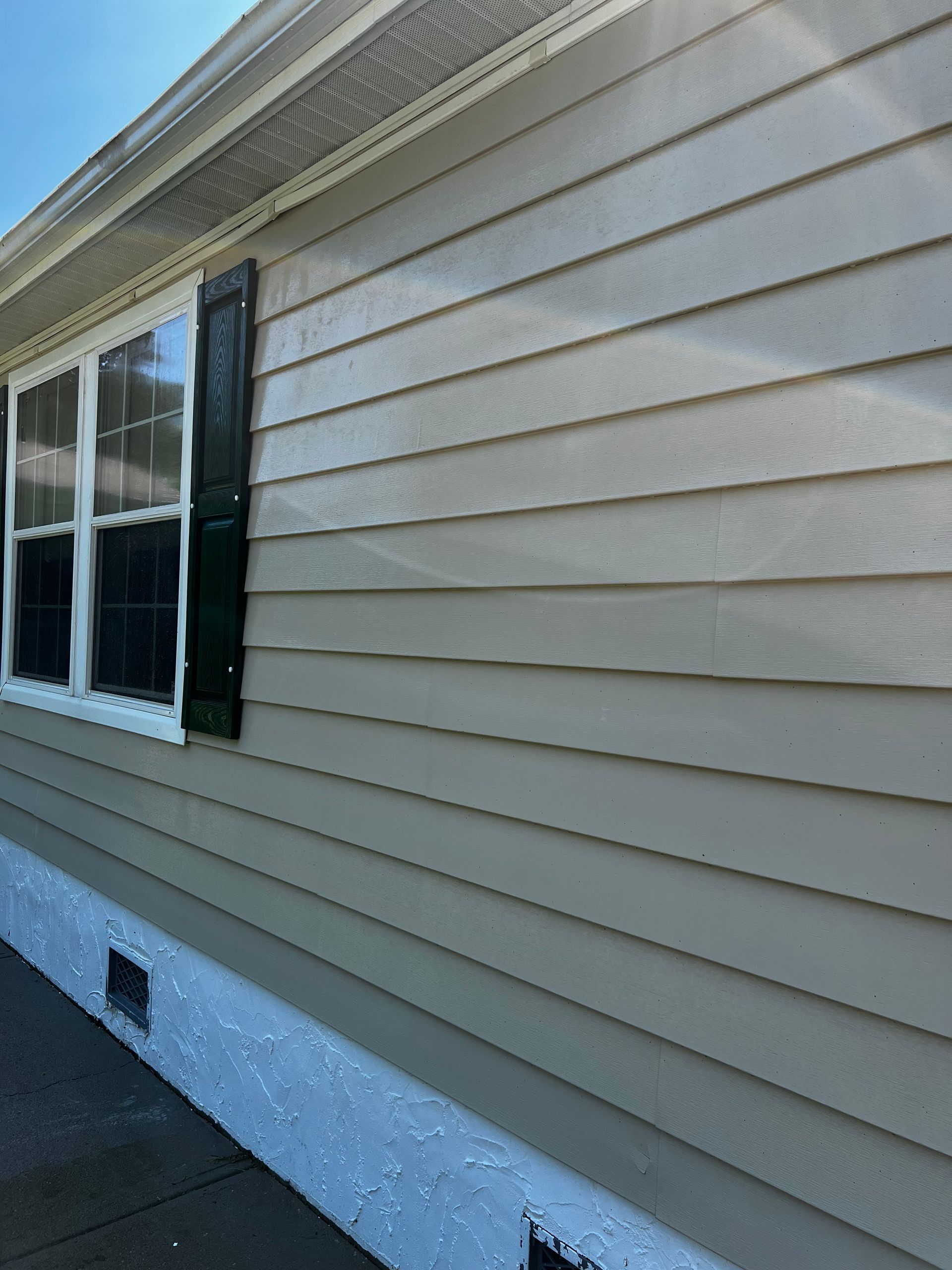 The side of a house with siding and black shutters