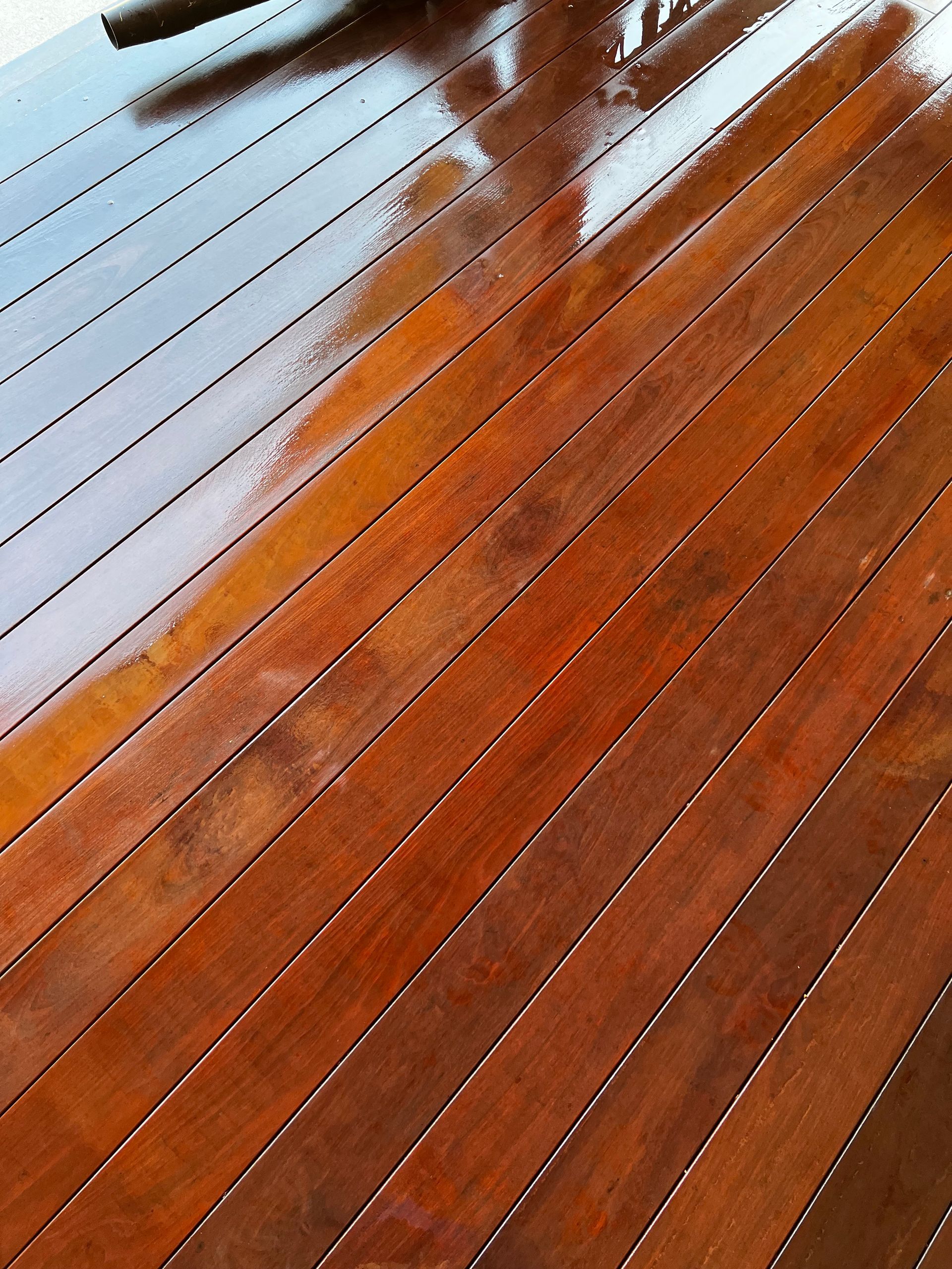 A close up of a wooden floor with a chair in the background