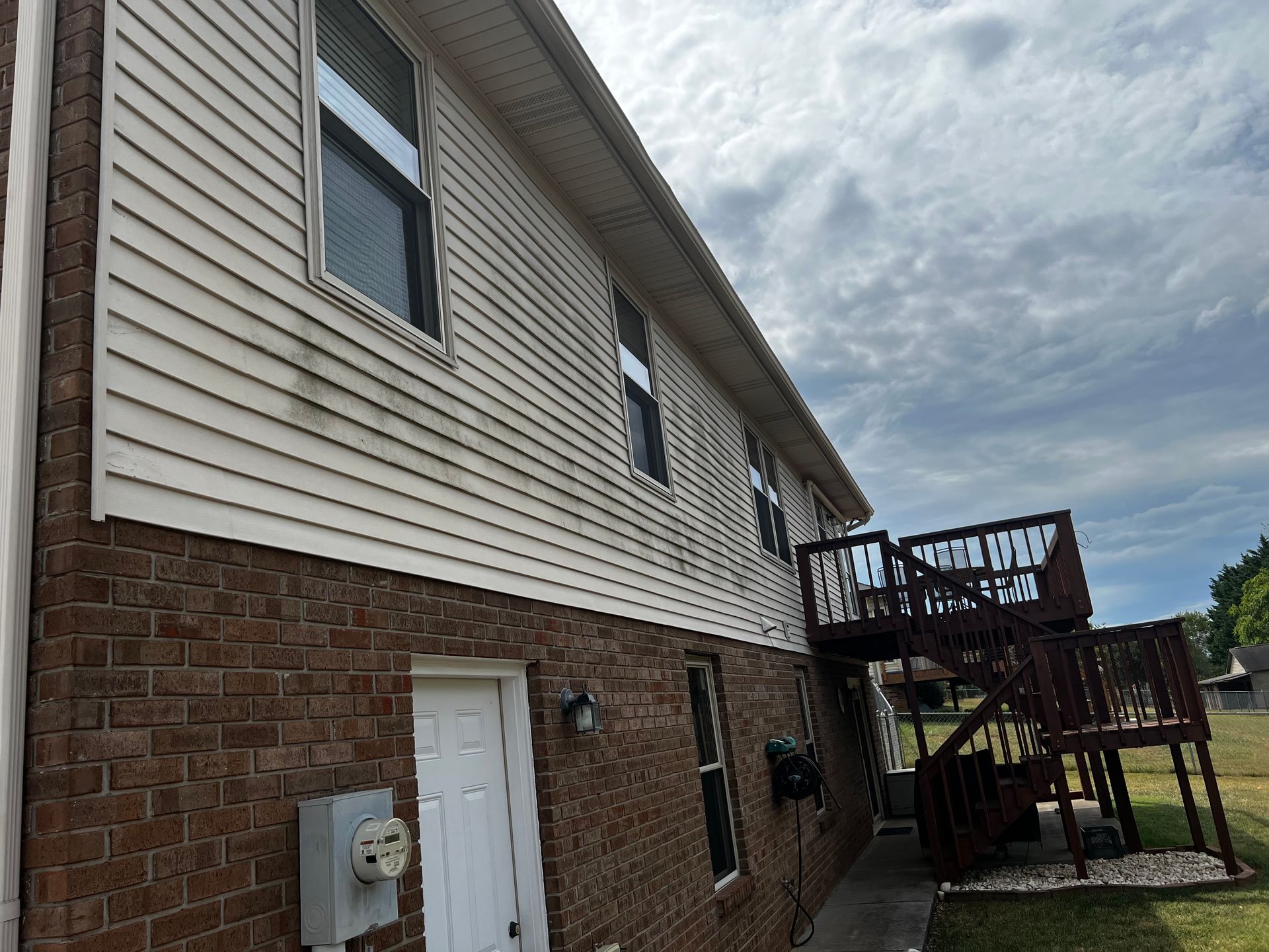 A large brick house with a white siding and a wooden deck. Job done by 865 Power Wash