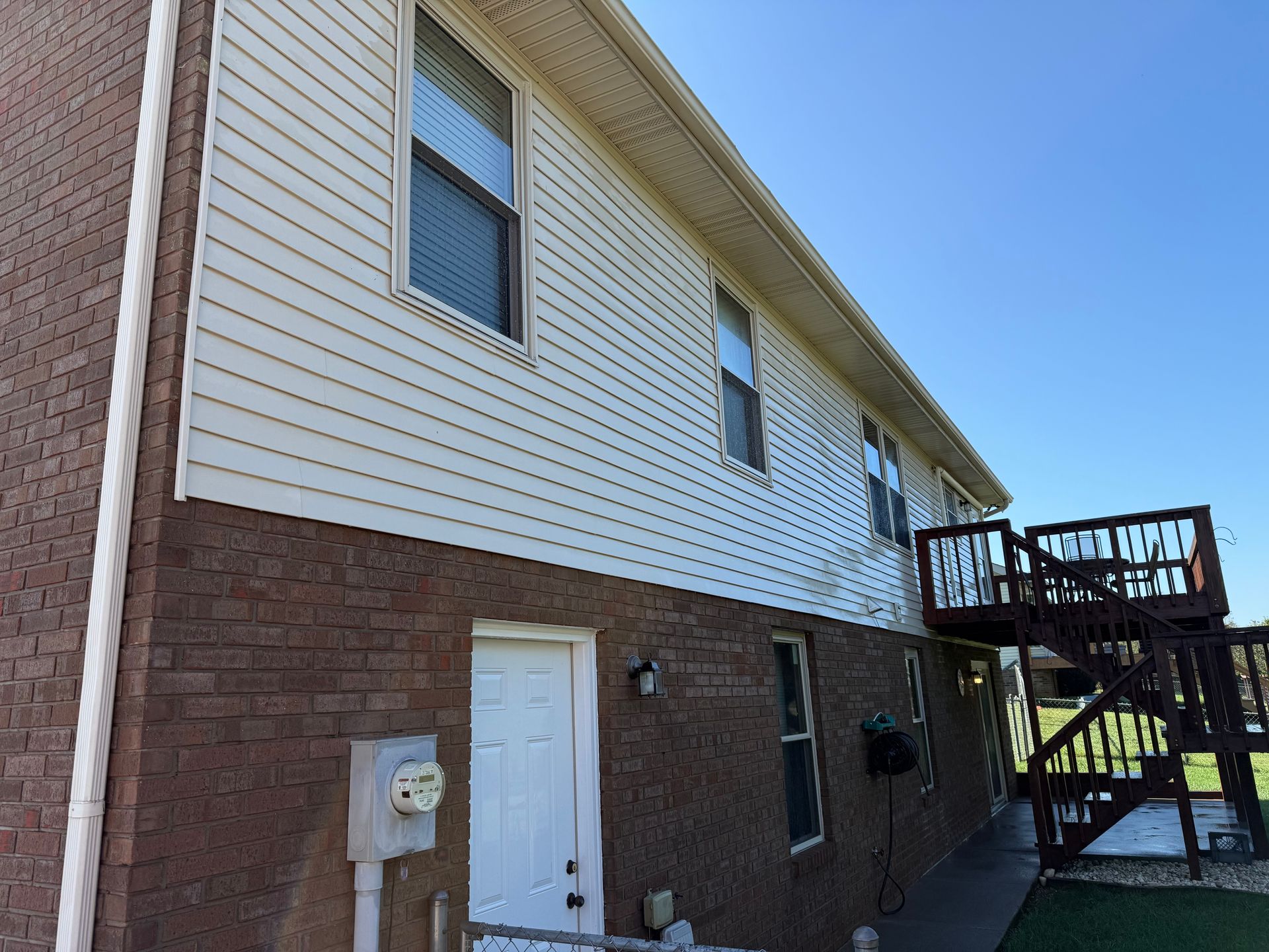 A large brick house with a white siding and a wooden deck. Job done by 865 Power Wash