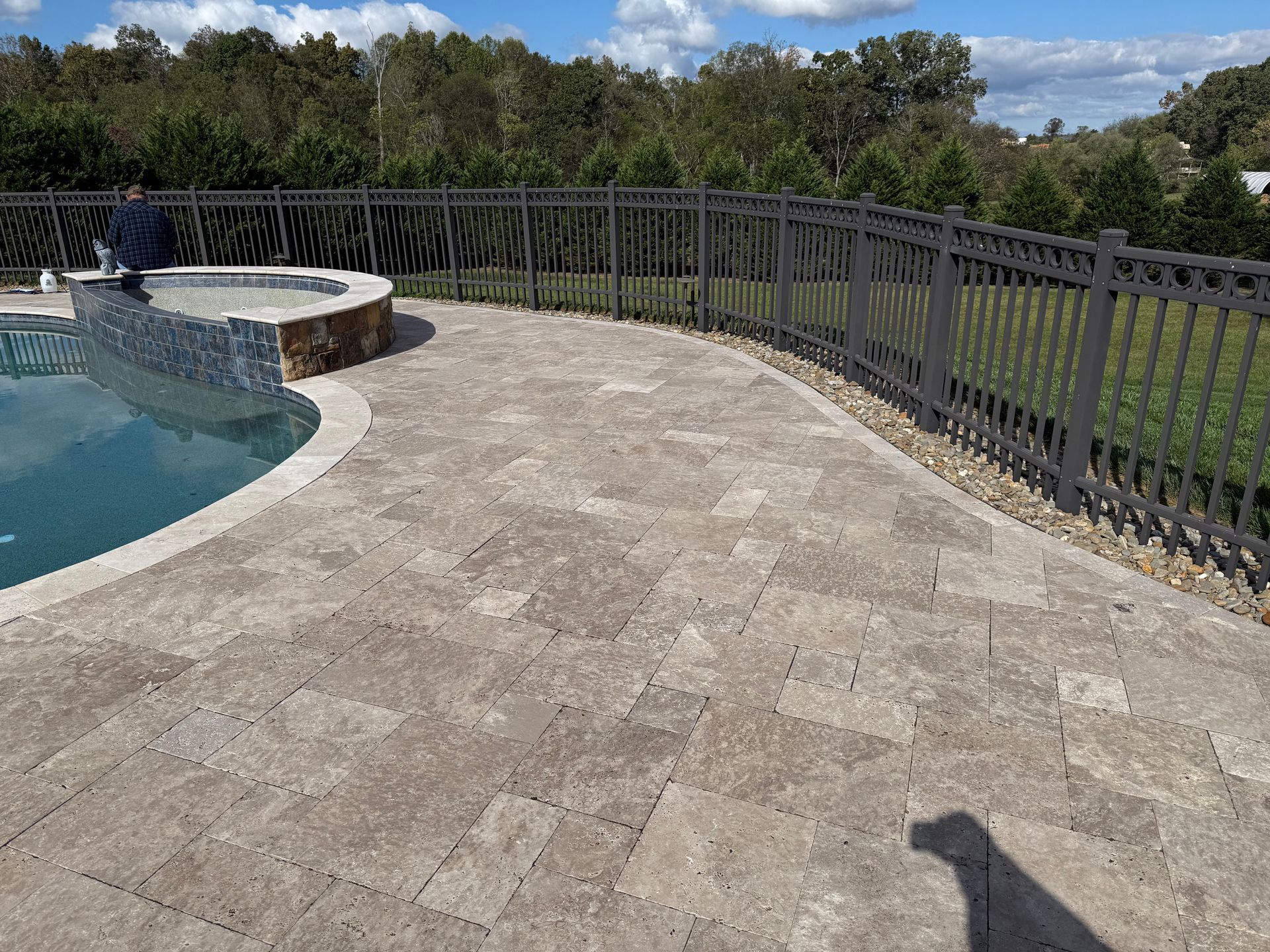A swimming pool with a fence around it and a patio. Paver sealed by 865 Power Wash