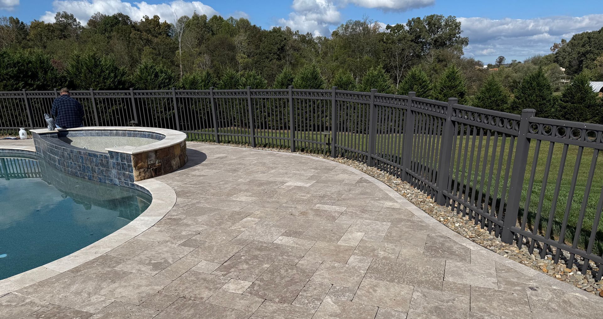 A fence surrounds a swimming pool in a backyard. Job done by 865 Power Wash
