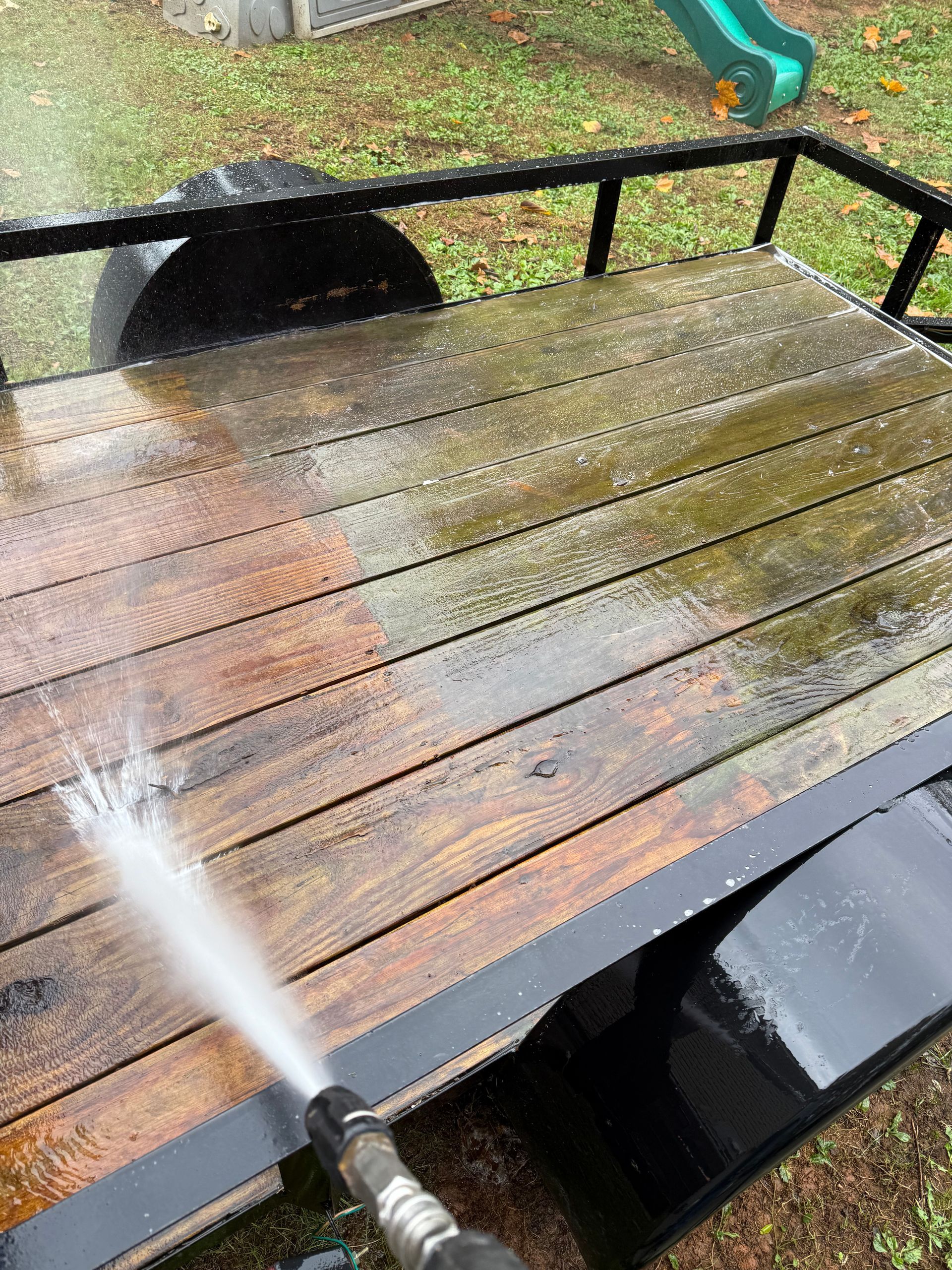 A person is cleaning a trailer with a high pressure washer.