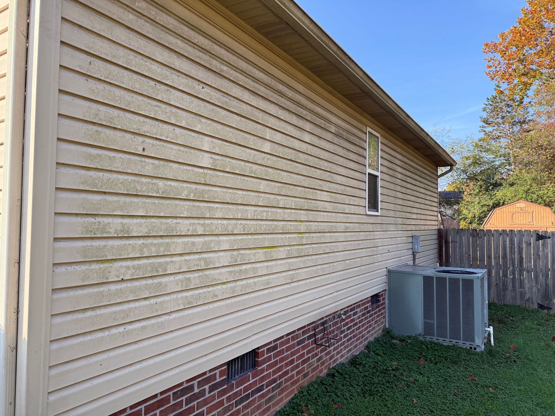 The side of a house with a brick foundation and siding.Job done by 865 Power Wash