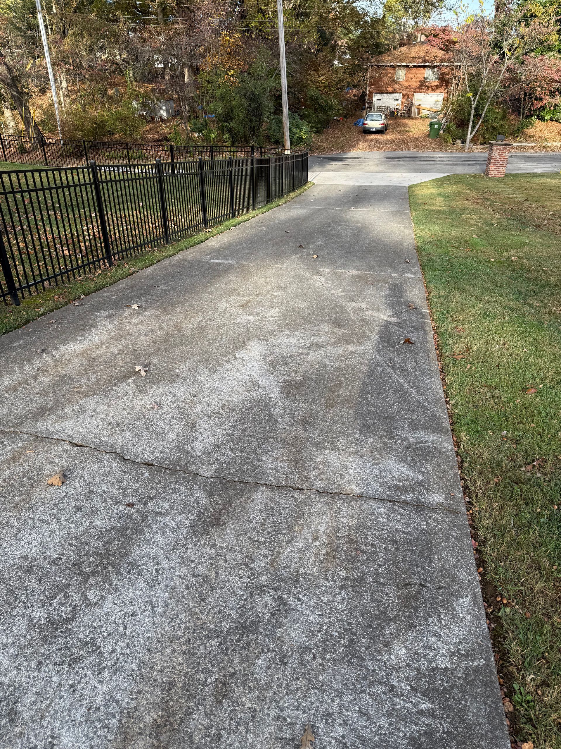 A concrete walkway leading to a house with a fence along the side of it.Cleaning by 865 Power Wash