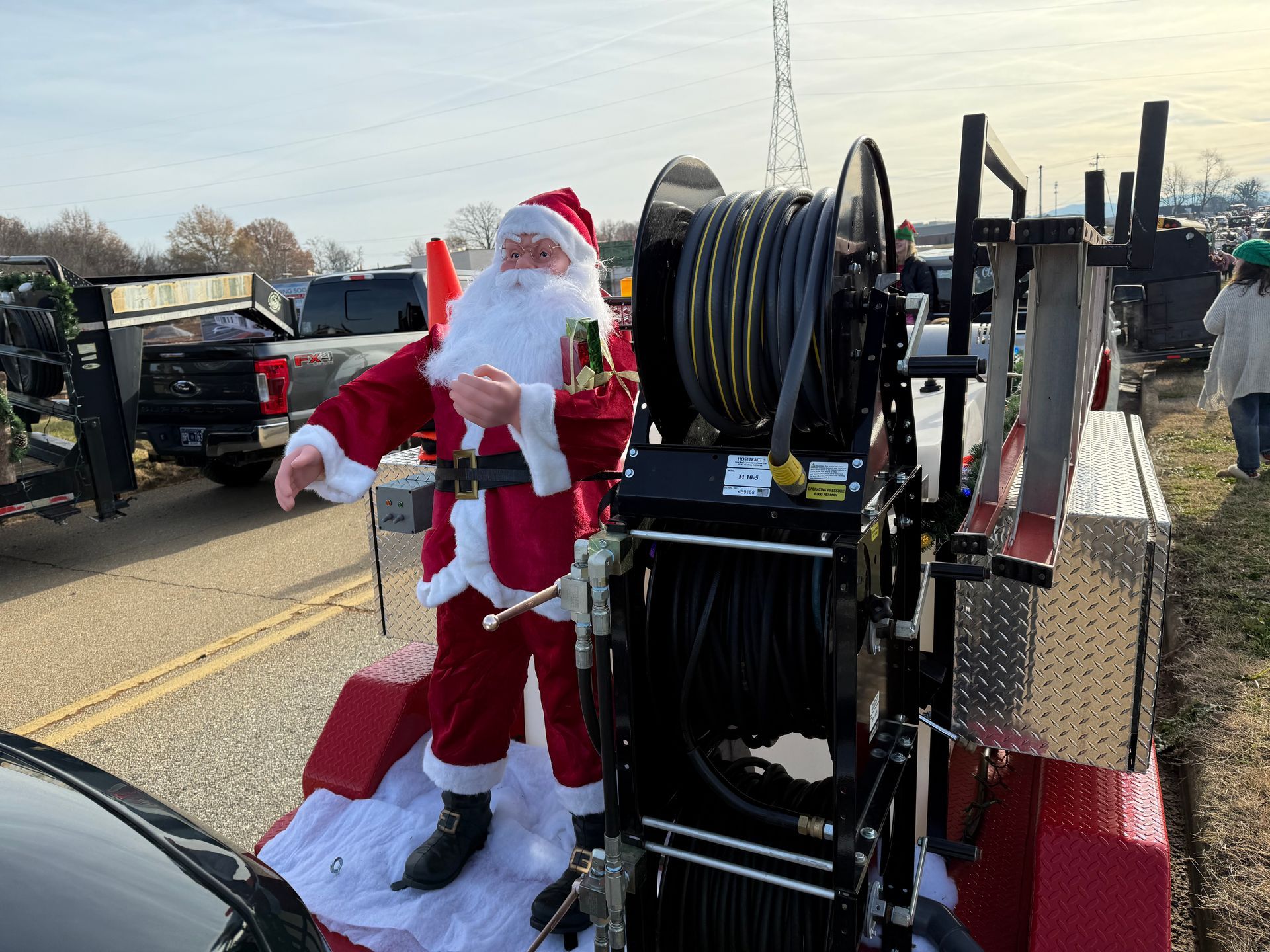 A statue of santa claus is standing next to a hose reel.